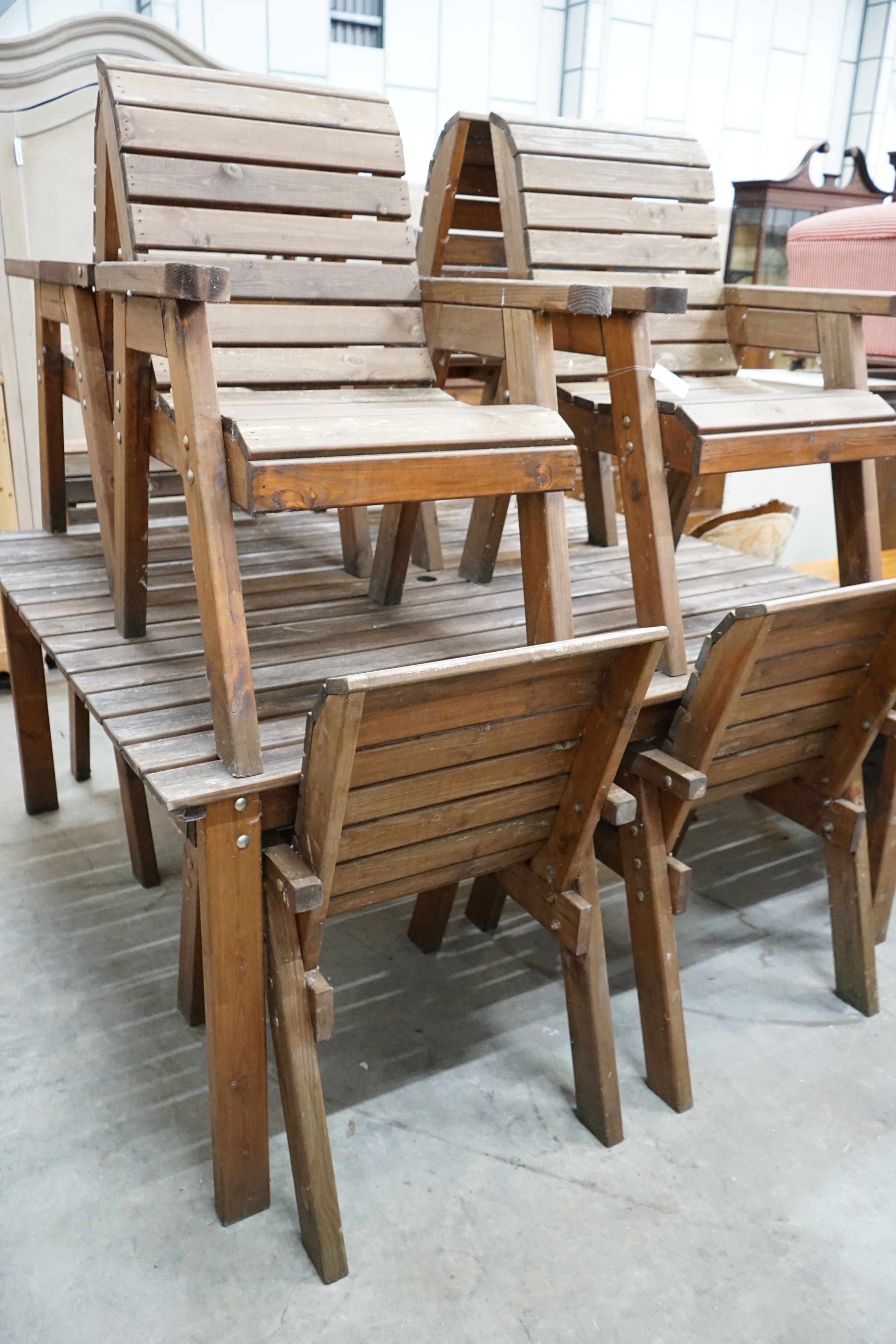 A large rectangular slatted wood garden table, length 174cm, depth 162cm, height 79cm together with eight matching elbow chairs